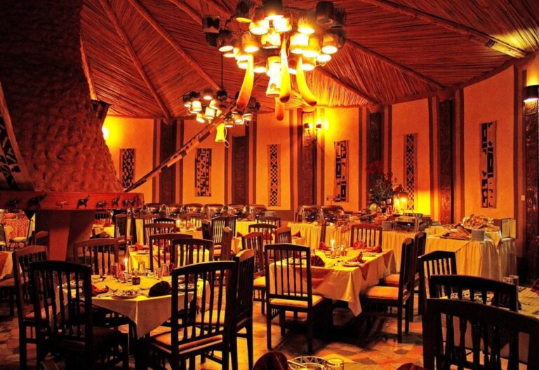 Jídelna restaurace večer, se stoly pod žlutými ubrusy a rozsvícenými lustry