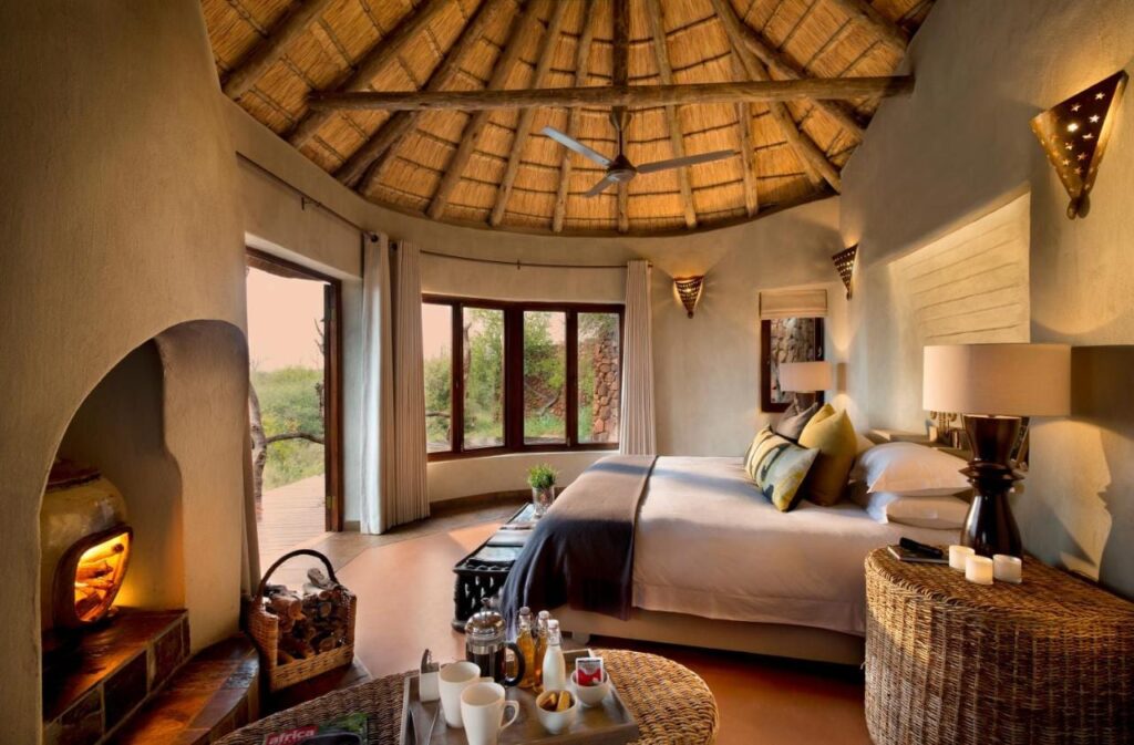 Apartmá Madikwe Safari Lodge pod doškovou střechou, s velkou postelí a zapáleným krbem