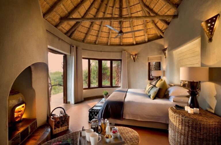 Apartmá Madikwe Safari Lodge pod doškovou střechou, s velkou postelí a zapáleným krbem