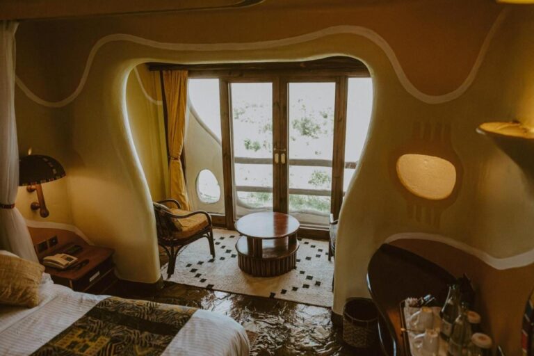 Pokoj Mara Serena Safari Lodge se zaoblenými zdmi a posezením před francouzským oknem na balkon