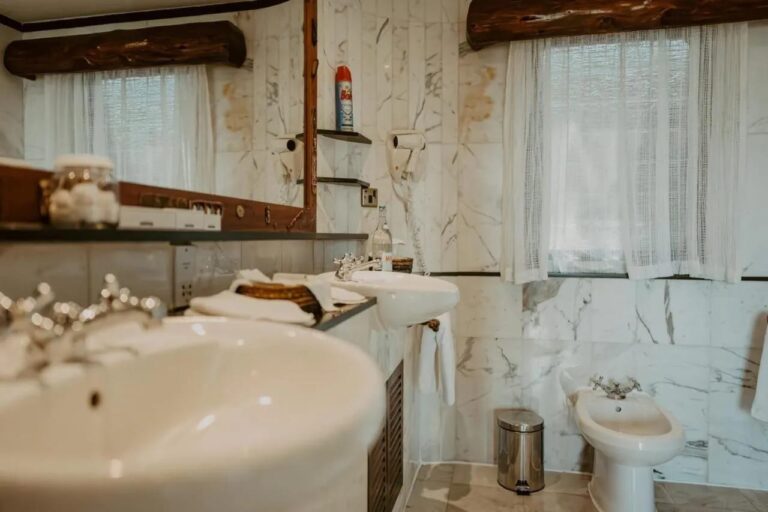 Detail umyvadla v mramorové koupelně, v pozadí bidet