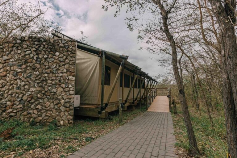 Stan lodge, napůl z kamene a napůl z plachtoviny, na konci dlážděné cesty