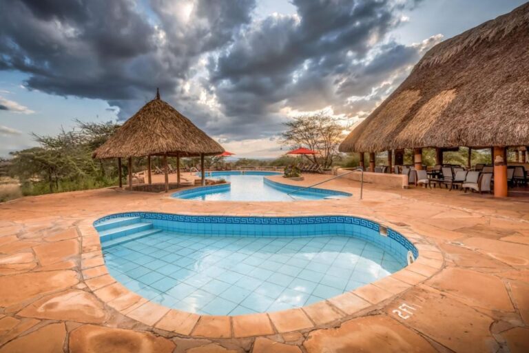 Malý obkládaný bazének v popředí a velký bazén Samburu Sopa Lodge mezi doškovým přístřeškem a terasou s doškovou střechou