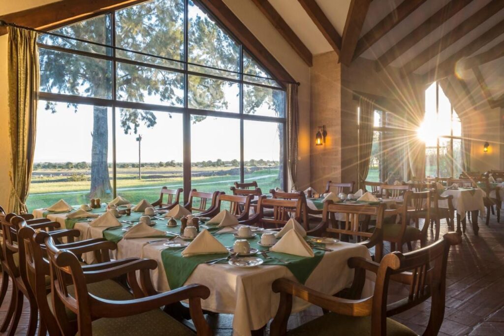 Restaurace Sweetwaters Serena Camp s prostřenými stoly před velkým oknem s výhledem na pláň