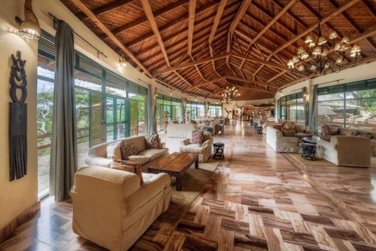Velký salonek lodge s křesly a velkými okny pod dřevěným krovem